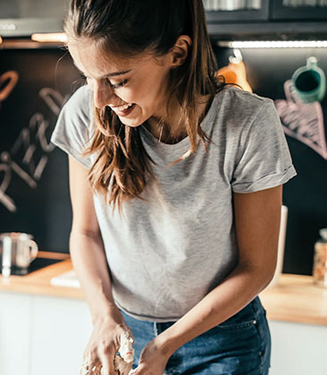 Mulher jovem sorridente cozinhando em um ambiente moderno.