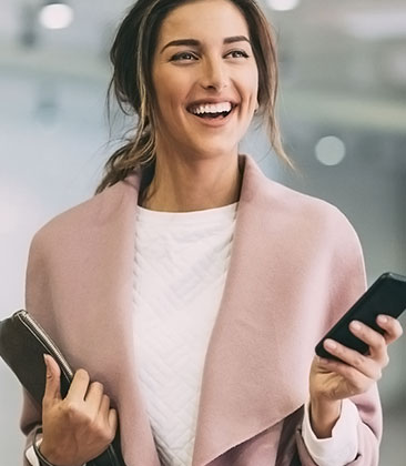 Mulher jovem elegante e sorridente segurando celular.